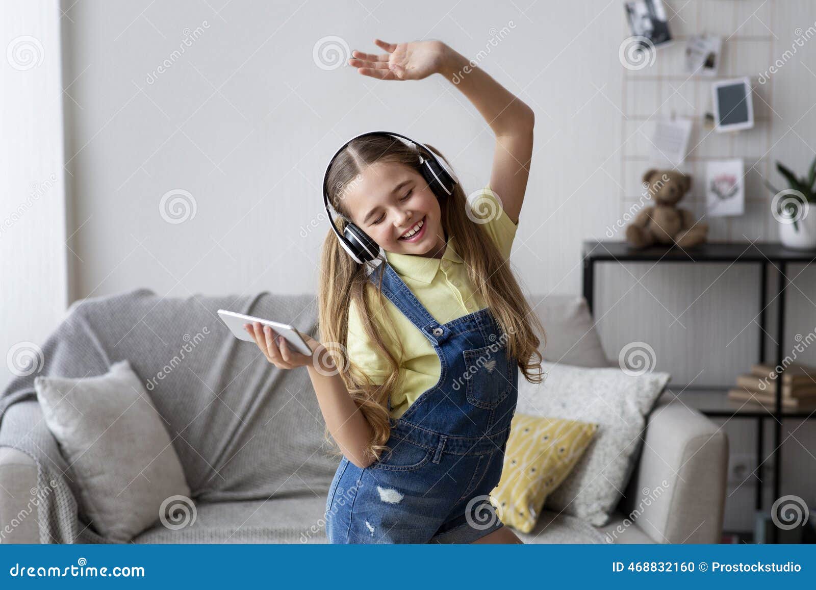 Young person dancing happily in a living room with headphones on